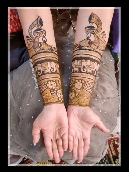 The start of a beautiful bridal mehendi. This design features peacock and elephant bands on the arms, setting the stage for the intricate work on the palms.