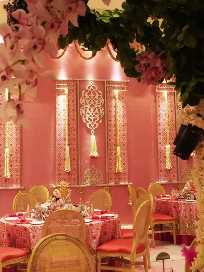 The dining setup for Anant and Radhika’s Raas Garba, adorned in hues of pink and patola fabric. The decor features ornate wall panels and traditional motifs, creating a vibrant and regal dining experience.