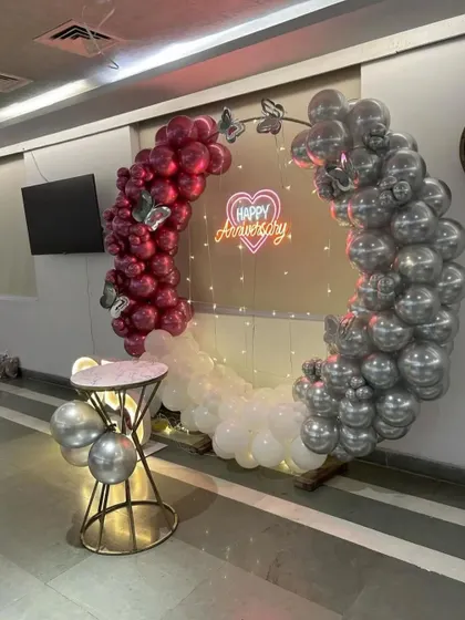 A side view of the anniversary balloon arch, showing the detail of the chrome and magenta balloons and the fairy lights inside the ring.