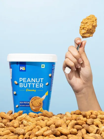 A simple, effective shot that highlights the delicious texture of creamy peanut butter. The hand holding up the spoonful makes the product feel instantly craveable and ready to eat.