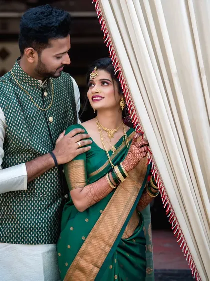 A sweet moment between the couple, framed by the wedding decor. The bride is dressed in a beautiful green saree, a popular choice for Maharashtrian wedding events.