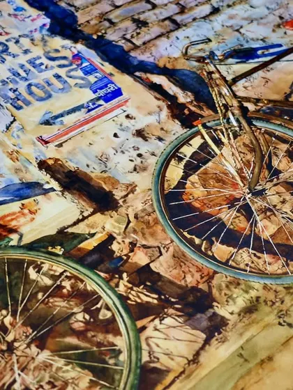 A close-up of the two-bicycle painting, focusing on the details of the wheels and the texture of the brick wall.