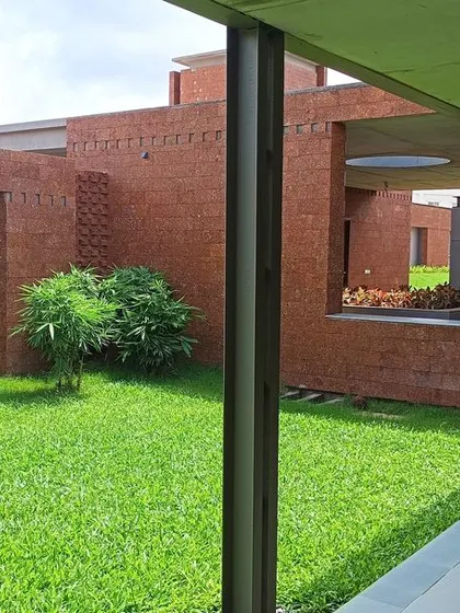 A green courtyard at the Bagchi Karunashraya hospice, featuring a unique wall sculpture. These landscaped pockets provide peaceful outdoor spaces for residents and staff.