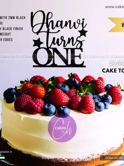 A classic vanilla cake topped with a generous amount of fresh berries. The simple, fresh design is elevated with a custom black acrylic topper for Dhanvi's first birthday.