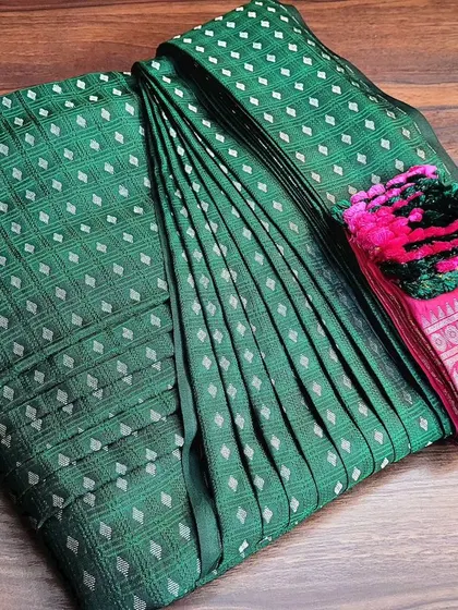 This green and pink silk saree is ready to be delivered to a client. The box fold keeps the entire drape, including the decorative tassels, safe and organized.