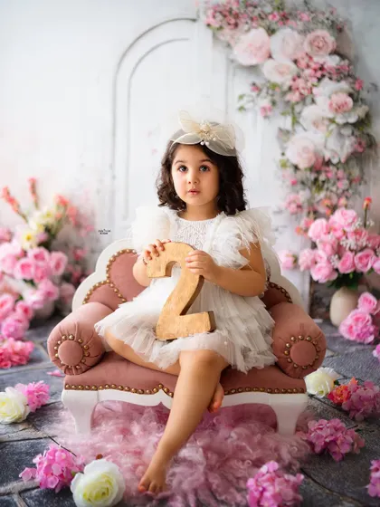 Holding up the number '2' to proudly mark her second birthday in this beautiful floral-themed session.
