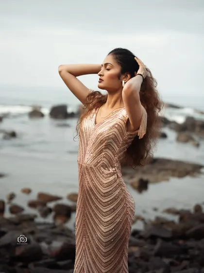 A beautiful portrait of a model in a shimmering gold gown on a rocky beach. The contrast between the glamorous dress and the rugged, natural setting creates a stunning and unexpected image.