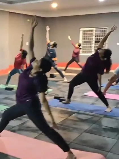 A group of members holding the reverse warrior pose during a yoga class. This pose builds strength in the legs and core while opening up the side body.