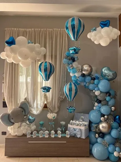 A classic "Welcome home baby boy" setup. The room is filled with blue and silver balloons, hot air balloon foils, and an adorable elephant balloon sculpture.