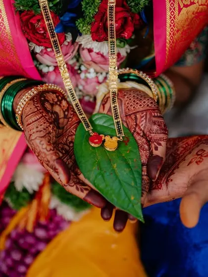 A beautiful detail shot of the Mangalsutra held in the couple's hands over a betel leaf.