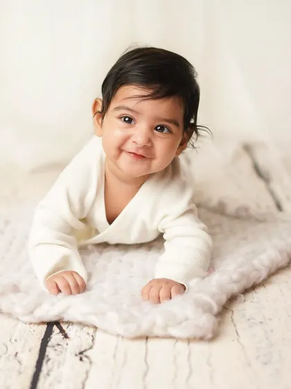 A big, proud smile from this little guy during his tummy time session. He's clearly happy to show off his new skills.