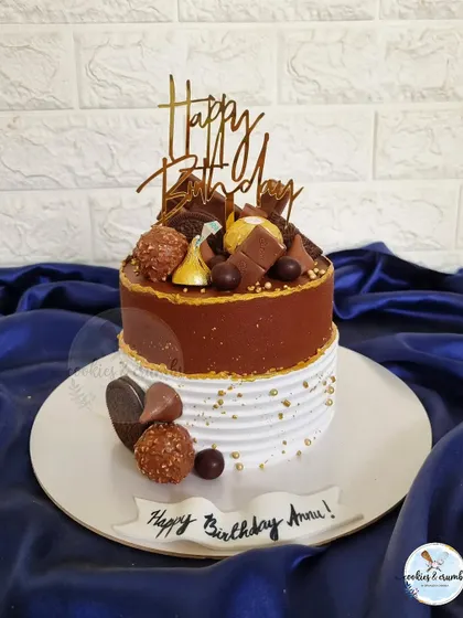 A chocolate overload cake that's a feast for the eyes. It's topped with a mountain of assorted chocolates like Ferrero Rocher and Hershey's Kisses.