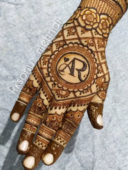 A duplicate of image 119, showing a close-up of the hand featuring the "AR" initial monogram. The central placement makes it a focal point, surrounded by delicate floral and lattice work.