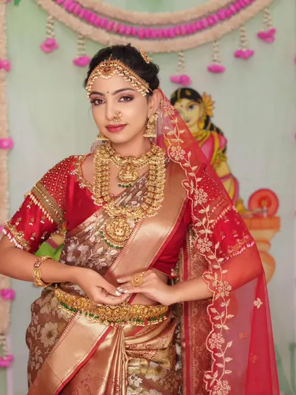 This look, created for a makeup masterclass, features a grand temple jewellery set. The layered necklaces and matha patti create a regal look against the red and gold saree.