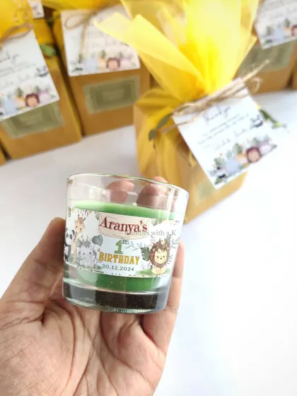 Holding one of the personalized candles for Aranya's first birthday, showing the cute animal-themed sticker.