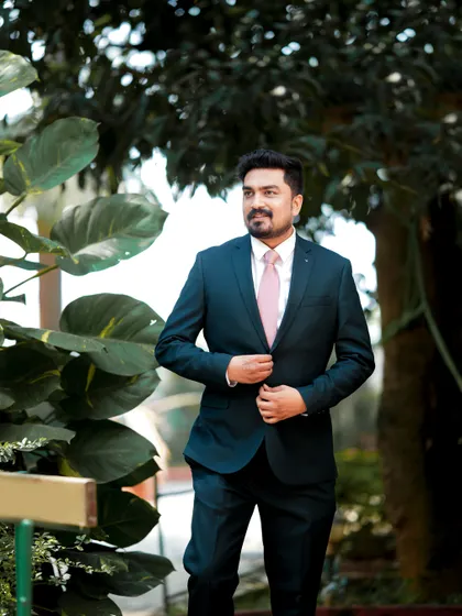 A candid shot of the groom looking dapper in a suit, captured in a natural garden setting.