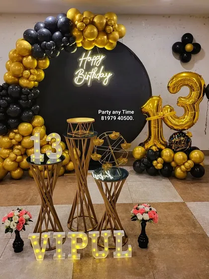 The full setup for Vipul's 13th birthday, featuring a circular backdrop, a balloon half-arch, and gold pedestals.