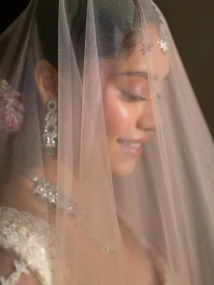 A smiling portrait through the veil. The look is ethereal and romantic, perfect for a bride who dreams of elegance and minimalism.