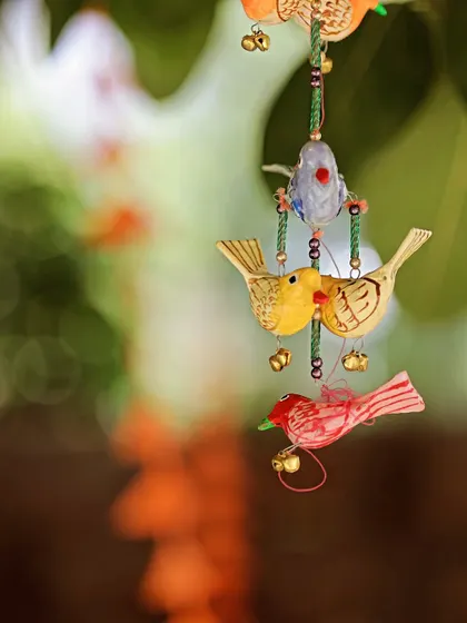 A close-up of a charming, hand-painted bird hanging, a small but delightful detail from a Haldi ceremony's decor.