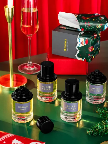 A festive Christmas setup for Fraganote, featuring their perfumes alongside holiday props like champagne and gift wrap. The composition is celebratory and luxurious, perfect for a seasonal social media campaign.