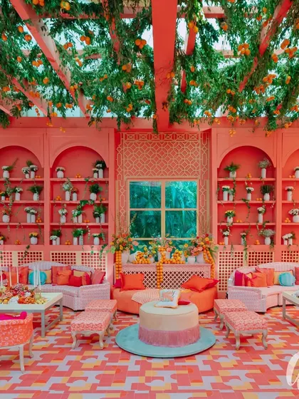 This seating area is defined by a ceiling trellis overflowing with greenery and oranges. The back wall features built-in shelves styled with plants and citrus, creating a lush, cohesive look that surrounds the guests.