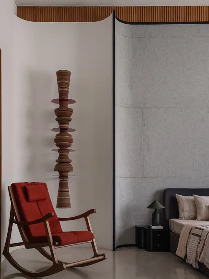 The parent's suite features a comfortable rocking chair set against a stunning wall-mounted wooden totem, creating a perfect corner for relaxation.