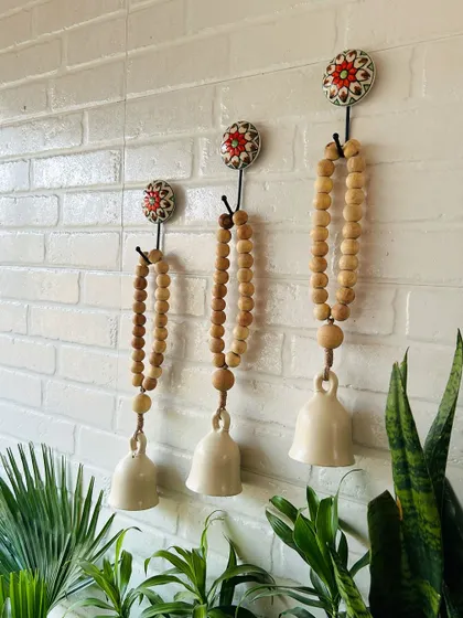 A side view of our classic white boho beaded ceramic bells. The combination of natural wooden beads, jute twine, and ivory ceramic creates a rustic and serene atmosphere, perfect for your balcony or garden.