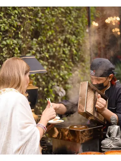 A guest is served freshly steamed dim sum directly from a traditional bamboo steamer, highlighting the interactive and authentic nature of our Pan-Asian stations.