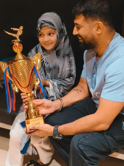 A young state champion holding her first-place trophy. This is a moment of pure joy and a testament to her incredible hard work and fighting spirit.