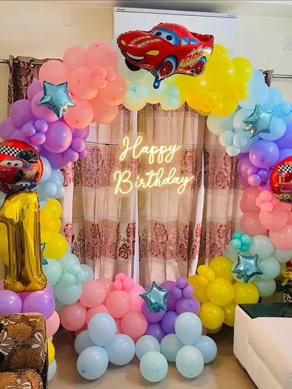 A colorful and fun "Cars" themed birthday party for an 11-year-old. This ring-shaped balloon arch is decorated with pastel-colored balloons and Lightning McQueen foil balloons.