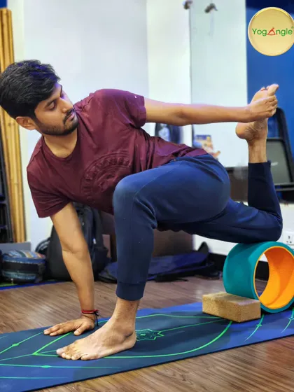 This student demonstrates a deep, twisting lunge using the yoga wheel and blocks for support. This combination of props allows him to explore the twist with stability, releasing tension in the spine and hips.