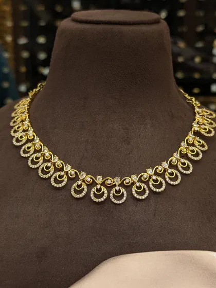 A beautiful and dainty necklace with sparkling AD stones. The design features small crescent and circle motifs, adding a touch of sparkle for any occasion.