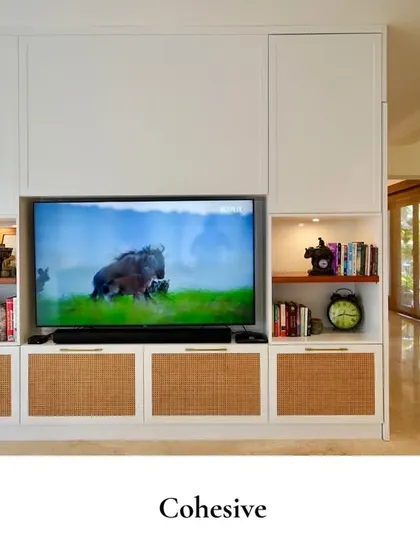 This living room blends style and practicality effortlessly. The built-in TV unit features rattan-paneled cabinets and open, lit shelving for books and decor.
