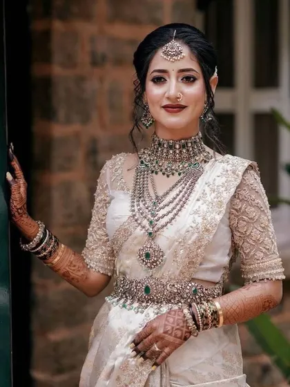 A close-up of the bride's beautiful smile and her stunning silver jewelry. The off-white saree and custom blouse create a look of pure sophistication.