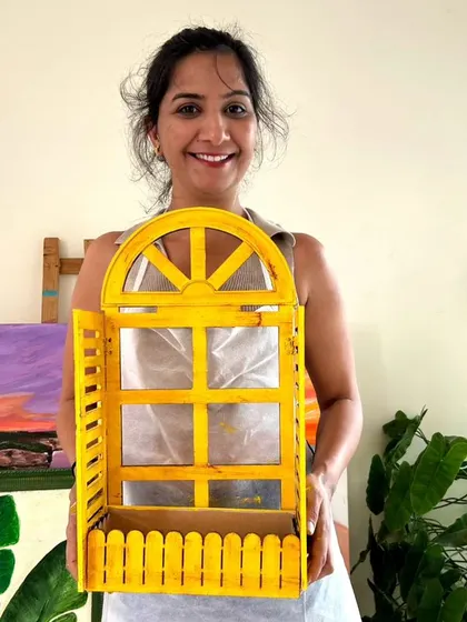 A participant proudly holding the cheerful yellow window-style planter she created in my wood distressing workshop. It's a perfect, rustic-chic addition to any home.