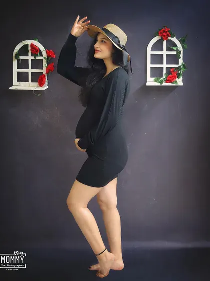 A chic and stylish solo maternity portrait. The mom-to-be rocks a simple black dress and a hat, showing that you can bring your own personal style to the studio shoot.