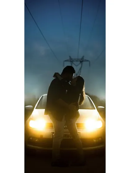 A full-length version of our creative car-light silhouette. This panoramic view emphasizes the dramatic lighting and the romantic isolation of the couple.