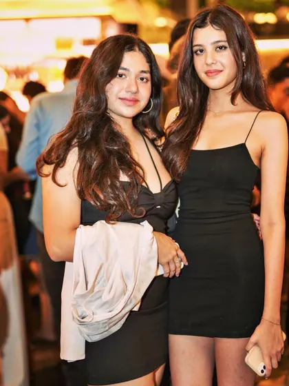 Two friends in classic black dresses, looking chic and ready for a night of house music.