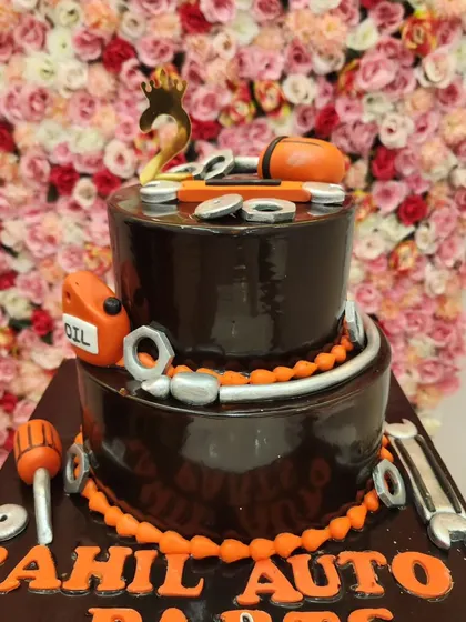 A two-tiered chocolate cake with an automobile theme. It's decorated with fondant tools, nuts, and bolts, perfect for a mechanic or car parts business.