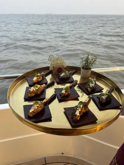 Grilled lamb chops with a creamy topping, served on individual black slate plates. This sophisticated appetizer is perfect for a sunset yacht party, offering a gourmet bite with a stunning ocean backdrop.