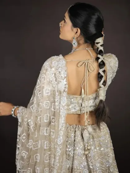 A back view of this stunning ivory lehenga, showing the stylish tie-up blouse design and the sheer embroidered dupatta.