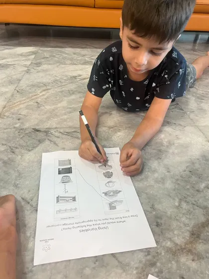 A child works diligently on his 'How to Code a Rollercoaster' worksheet. This activity helps solidify concepts like sequencing and variables in a simple, age-appropriate way.