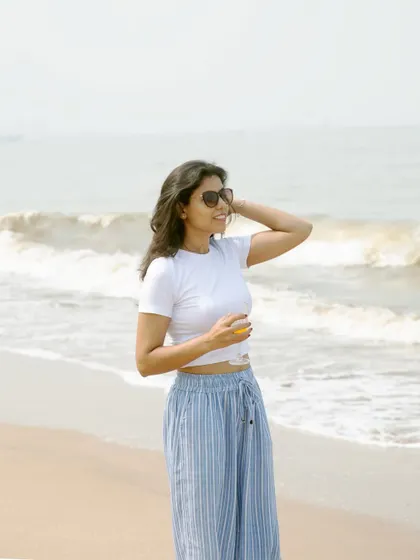 A classic beach pose, looking out at the ocean. This image is great for travel, wellness, or casual fashion content.