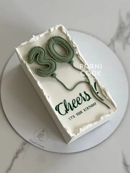 A modern and minimalist rectangular cake for a 30th birthday. The clean design with the trendy balloon number topper is effortlessly chic.