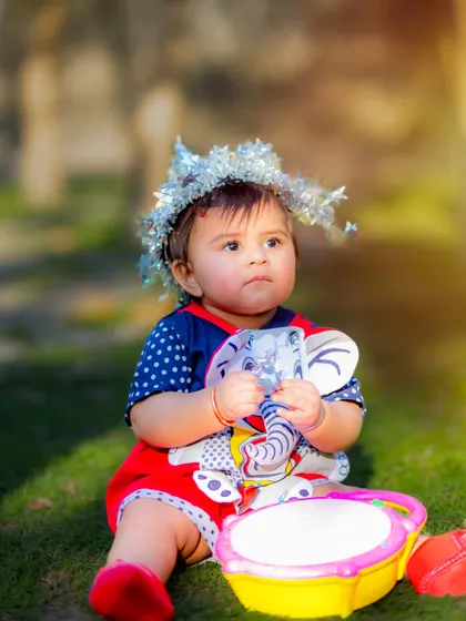 A sweet baby boy enjoying an outdoor photoshoot with his toys. The soft, natural light of the late afternoon creates a warm and gentle mood.