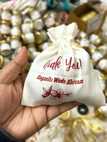 A custom-printed potli bag for a wedding favor. The bag itself becomes part of the gift, printed with a thank you message and the couple's names.