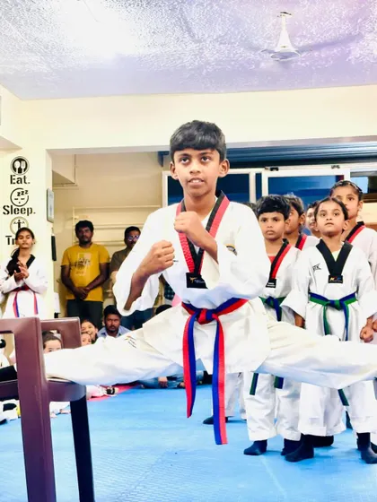 This student shows incredible flexibility and strength, performing a split between two chairs as part of his belt test demonstration.