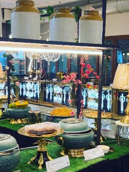 A beautiful buffet display featuring elegant serving dishes and decorative lamps. Our unique presentation style is designed to make the food setup a glamorous highlight of your event.