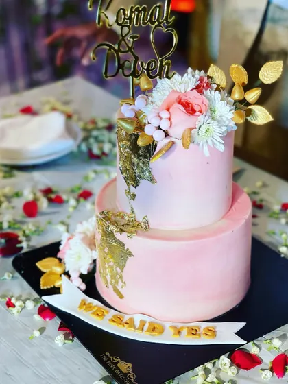 Another view of the lovely pink and gold "We Said Yes" engagement cake, showing the custom couple's name topper and delicate floral arrangement.