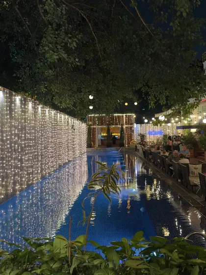 Aqua by night, decorated with festive fairy lights for Deepawali. The reflection on the pool surface creates a magical, shimmering atmosphere for our guests.